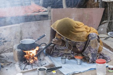 Pushkar, Hindistan - 13 Kasım 2018: Hintli kadın Hindistan 'ın Rajasthan çölünün yakınındaki avluda ailesi için çay yapıyor.