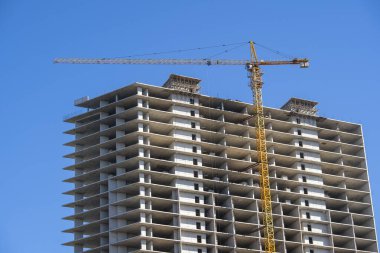 Yüksek katlı bir vinç ile bina inşaatı. Bina inşaat kalıp kullanarak. İnşaat Vinç ve mavi gökyüzü karşı bina.