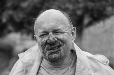 Yağmurda su birikintisine düştükten sonra kirli yüzlü bir adamın portresi. Yaklaş. Siyah ve beyaz