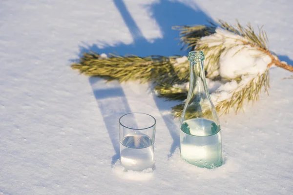 冬の白い雪の上のガラス瓶と水のガラス 閉じる — ストック写真