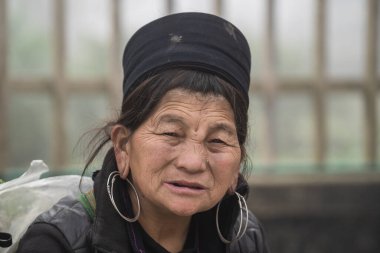 Sapa, Vietnam - Mart 06, 2020: Geleneksel kıyafet ve mücevher giyen etnik Hmong kadını turistlerin Sapa, Kuzey Vietnam 'daki dağ köyünde el sanatları satmalarını bekliyor