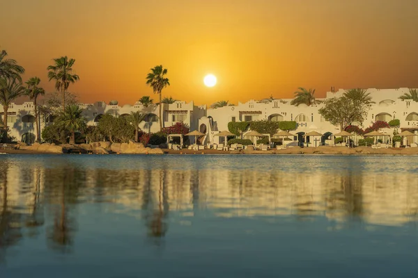 Binalar, güneş panelleri ve şemsiyeler, sabah Sharm El Sheikh 'in sahil kasabasındaki sakin deniz suyuna yansıtılır.