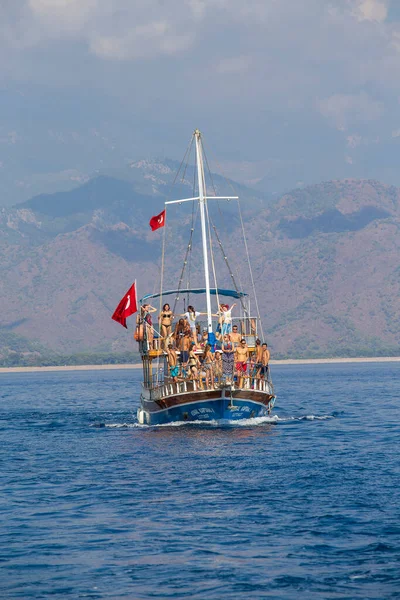 Kemer, Türkiye - 23 Ekim 2017: Turistlerle dolu renkli bir tekne Kemer plajından dönüyor. Kemer turistler arasında çok popülerdir..