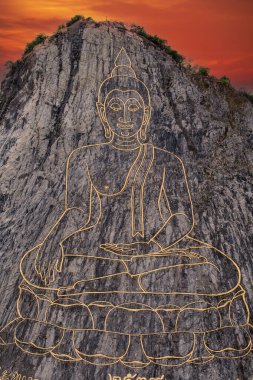 Kızıl gökyüzü arka planındaki kayanın üzerinde Altın Büyük Buda, Pattaya, Tayland