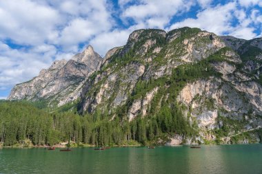 Lago di Braies, İtalya - 26 Ağustos 2021: İnsanlar Alp Gölü Braies, İtalya 'da tahtadan yapılmış geleneksel tekneleri kürek çekiyorlar. Dolomitlerdeki resimli dağ gölü