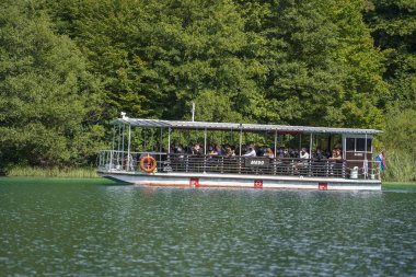 Plitvice Gölleri, Hırvatistan - 30 Ağustos 2021: İnsanlar yaz aylarında Hırvatistan, Orta Avrupa, seyahat ve doğa kavramları ile Plitvice Gölleri kıyıları boyunca turistik bir tekneye biniyor