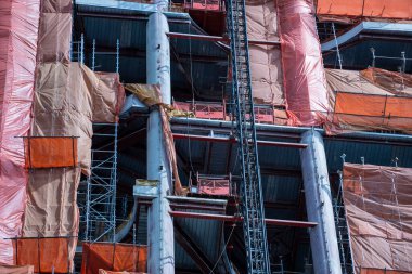Şehrin güvenlik ve yasal uyum için yapı iskelesini koruyucu ağ kaplıyor. İskeleli inşaat alanı