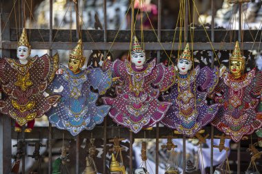 Burma 'daki sokak pazarındaki turist tezgahında renkli kuklalar. Myanmar 'da satılık eşyalar. Vitrinde asılı duran el yapımı bebekler