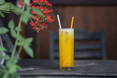 Mango ve portakallı tropikal meyve suyu ile sokak kafesindeki ahşap masada, yakın plan, Vietnam