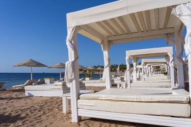 Mısır, Afrika 'daki Kızıldeniz kıyısındaki tropikal tatil beldesinde lüks kumsalda yataklı beyaz güneş tepe örtüsü. Karantina sırasında boş plajlar