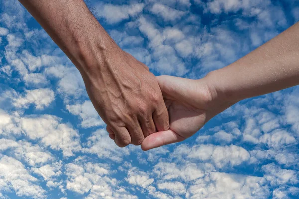 白い雲の背景を持つ青い空に開催されたカップルの手を閉じます — ストック写真