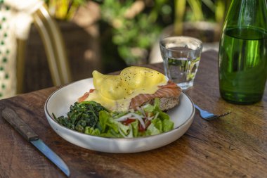 Ekşi ekmek, haşlanmış yumurta, somon, hollandez, sotelenmiş et ve taze sebzeler kafede, kapayın.