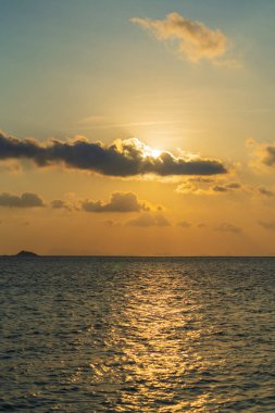 Tayland 'ın Koh Phangan adasında, deniz suyunda gün batımında kürek çeken bir adamın silueti. Denizde aktif dinlenme