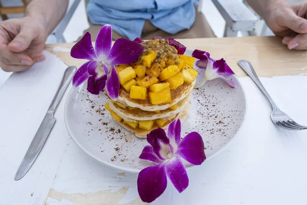 美味的煎饼 热带水果放在盘子里 放在咖啡厅的桌子上 健康的早餐用芒果 龙果和西番莲花装饰的美味薄饼 — 图库照片