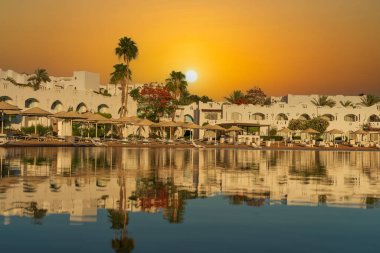 Binalar, güneş panelleri ve şemsiyeler, sabah Sharm El Sheikh 'in sahil kasabasındaki sakin deniz suyuna yansıtılır.