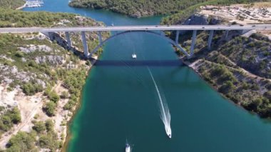 Hırvatistan, Orta Avrupa 'da yaz güneşli bir günde Krka nehri, otostrada ve kemer köprüsünün üzerinde uçmak, seyahat ve doğa kavramı. Güzel manzara ve büyük köprüsü olan mavi deniz. Havadan panorama görünümü