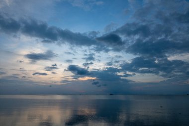 Tayland 'daki Koh Phangan adasında deniz suyunun üzerinde güzel bir günbatımı. Seyahat ve doğa kavramı. Akşam gökyüzü, bulutlar, güneş ve deniz suyu