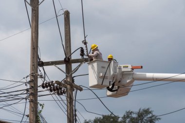 Koh Phangan, Tayland - Jan, 26, 2022: Gezici vinç kovasında duran iki erkek elektrikçi Tayland 'ın Koh Phangan adasındaki elektrik hattının kablosunu tamir ediyor