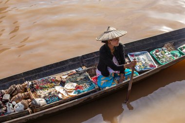 Inle Gölü, Myanmar - 14 Ocak 2016: Birmanyalı kadın küçük tahta bir teknede hediyelik eşya, incik boncuk ve bijouterieat the floater market, Inle Lake, Myanmar