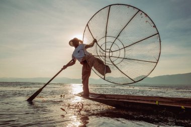 Inle Gölü, Myanmar - 14 Ocak 2016: Bambu teknesinde Burmalı balıkçı el yapımı ağla geleneksel balık yakalıyor. Inle Gölü, Myanmar, Burma