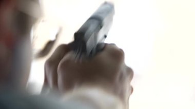 Bir adam atış poligonundaki hedeflere silahla ateş ediyor, yakın çekim, bulanık odak. Eğitimde, ağır çekimde, hedefe ateş eden bir adamın arka görüntüsü.