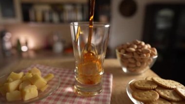 Mutfaktaki dönen masanın üzerine bira dökerek. Yavaş çekimde kapat. Masa bira, peynir, fıstık ve kurabiyelerle dönüyor.