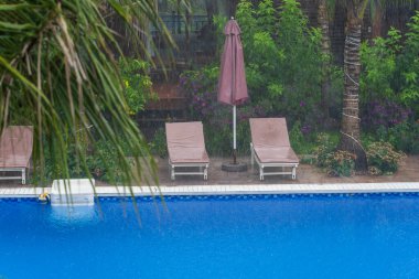 Tropik yaz yağmurları, yüzme havuzuna düşen yağmur damlaları Phu Quoc Adası, Vietnam, Güneydoğu Asya 'daki deniz kıyısında. Doğa ve çevre kavramı