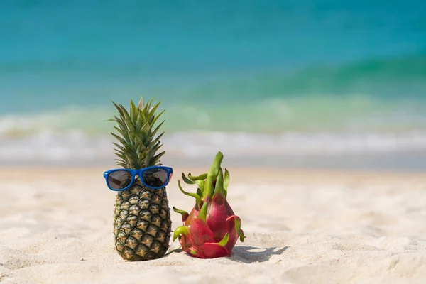 ターコイズブルーの海の水 タイに対して砂の熱帯ビーチでサングラスとピンクのドラゴンフルーツで魅力的なパイナップルを熟す 夏休みのコンセプト — ストック写真