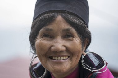 Sapa, Vietnam - Mart 06, 2020: Geleneksel kıyafet ve mücevher giyen etnik Hmong kadını turistlerin Sapa, Kuzey Vietnam 'daki dağ köyünde el sanatları satmalarını bekliyor