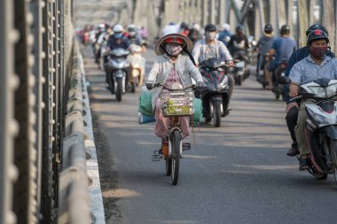 Hue, Vietnam - 12 Mart 2020 Hue kasabasındaki nehir üzerindeki otomobil ve yaya çelik köprüsü. Bisikletli ve motosikletli insanlar köprüden karşıya geçiyor.
