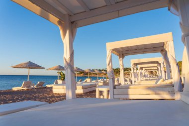 Mısır, Afrika 'daki Kızıldeniz kıyısındaki tropikal tatil beldesinde lüks kumsalda yataklı beyaz güneş tepe örtüsü. Karantina sırasında boş plajlar