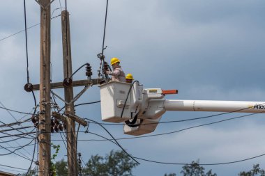 Koh Phangan, Tayland - Jan, 26, 2022: Gezici vinç kovasında duran iki erkek elektrikçi Tayland 'ın Koh Phangan adasındaki elektrik hattının kablosunu tamir ediyor