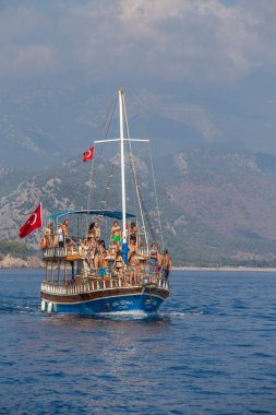Kemer, Türkiye - 23 Ekim 2017: Turistlerle dolu renkli bir tekne Kemer plajından dönüyor. Kemer turistler arasında çok popülerdir..