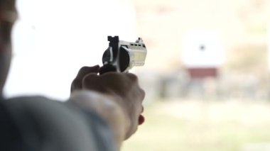 Adam atış poligonundaki hedeflere tabancayla ateş ediyor. Yaklaş, bulanık odaklan. Atış talimi yaparken arkadan ateş eden bir adamın görüntüsü. Yavaş çekim