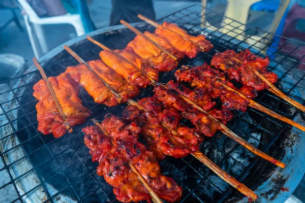 Tayland 'da Koh Phangan adasındaki bir gece marketinde odun sopasıyla ızgarada ızgara tavuk eti, yakın.
