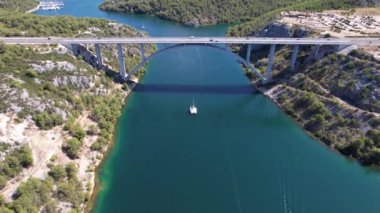 Hırvatistan, Orta Avrupa 'da yaz güneşli bir günde Krka nehri, otostrada ve kemer köprüsünün üzerinde uçmak, seyahat ve doğa kavramı. Güzel manzara ve büyük köprüsü olan mavi deniz. Havadan panorama görünümü