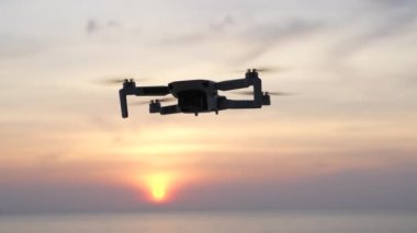 Koh Phangan, Tayland - Jan, 28, 2022: DJI Maviç mini insansız hava aracı gün batımında deniz suyunun yanında doğa önünde geziniyor