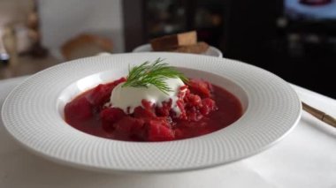 Geleneksel Ukrayna kırmızı çorbası veya kırmızı pancar, patates, havuç, lahana, beyaz kasede fasulye, yakın çekim. Bir tabak kırmızı pancar çorbası çorbası masada döner. Geleneksel Ukrayna yemekleri