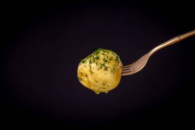 Siyah arka planda haşlanmış taze patatesli çatal. Kapat.