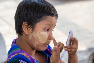 Mandalay, Myanmar, Burma - 16 Ocak 2016: Mandalay, Myanmar 'da gülen suratında Thanaka olan mutlu genç Myanmar kızı