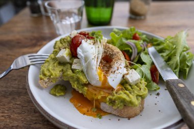 Ekşi ekmek, haşlanmış yumurta, avokado hamuru ve kafede taze sebzeler, kapanış, kahvaltı zamanı.
