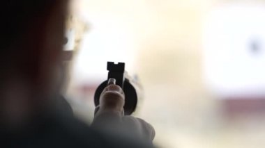 Adam atış poligonundaki hedeflere tabancayla ateş ediyor. Yaklaş, bulanık odaklan. Atış talimi yaparken arkadan ateş eden bir adamın görüntüsü. Yavaş çekim