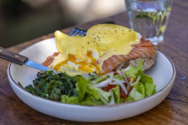 Ekşi ekmek, haşlanmış yumurta, somon, hollandez, sotelenmiş et ve taze sebzeler kafede, kapayın.