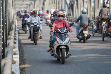 Hue, Vietnam - 12 Mart 2020 Hue kasabasındaki nehir üzerindeki otomobil ve yaya çelik köprüsü. Bisikletli ve motosikletli insanlar köprüden karşıya geçiyor.