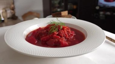 Geleneksel Ukrayna kırmızı çorbası veya kırmızı pancar, patates, havuç, lahana, beyaz kasede fasulye, yakın çekim. Bir tabak kırmızı pancar çorbası çorbası masada döner. Geleneksel Ukrayna yemekleri
