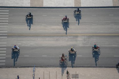 Nha Trang, Vietnam - 16 Nisan 2020: Nha Trang, Vietnam 'da deniz kenarında bir sahil yolunda sabah trafiği. Gün doğumunda motosikletlerin önünden geçmesinin gölgesi, hava manzarası