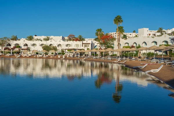 Gebäude Liegestühle Und Sonnenschirme Spiegeln Sich Ruhigen Meerwasser Strand Des — Stockfoto