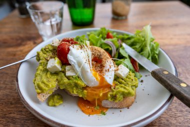 Ekşi ekmek, haşlanmış yumurta, avokado hamuru ve kafede taze sebzeler, kapanış, kahvaltı zamanı.