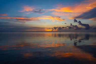 Tayland 'daki Koh Phangan adasında deniz suyunun üzerinde güzel bir günbatımı. Seyahat ve doğa kavramı. Akşam gökyüzü, bulutlar, güneş ve deniz suyu. Denizin üzerinde harika bir bulut