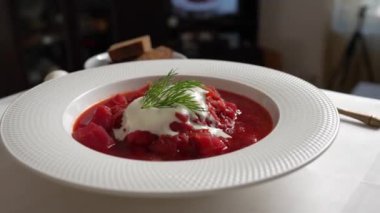 Geleneksel Ukrayna kırmızı çorbası veya kırmızı pancar, patates, havuç, lahana, beyaz kasede fasulye, yakın çekim. Bir tabak kırmızı pancar çorbası çorbası masada döner. Geleneksel Ukrayna yemekleri